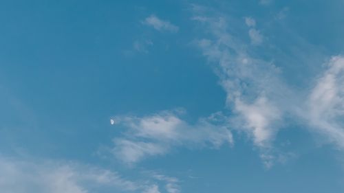 Free A serene view of a blue sky with scattered white clouds and a visible half moon during the day. Stock Photo
