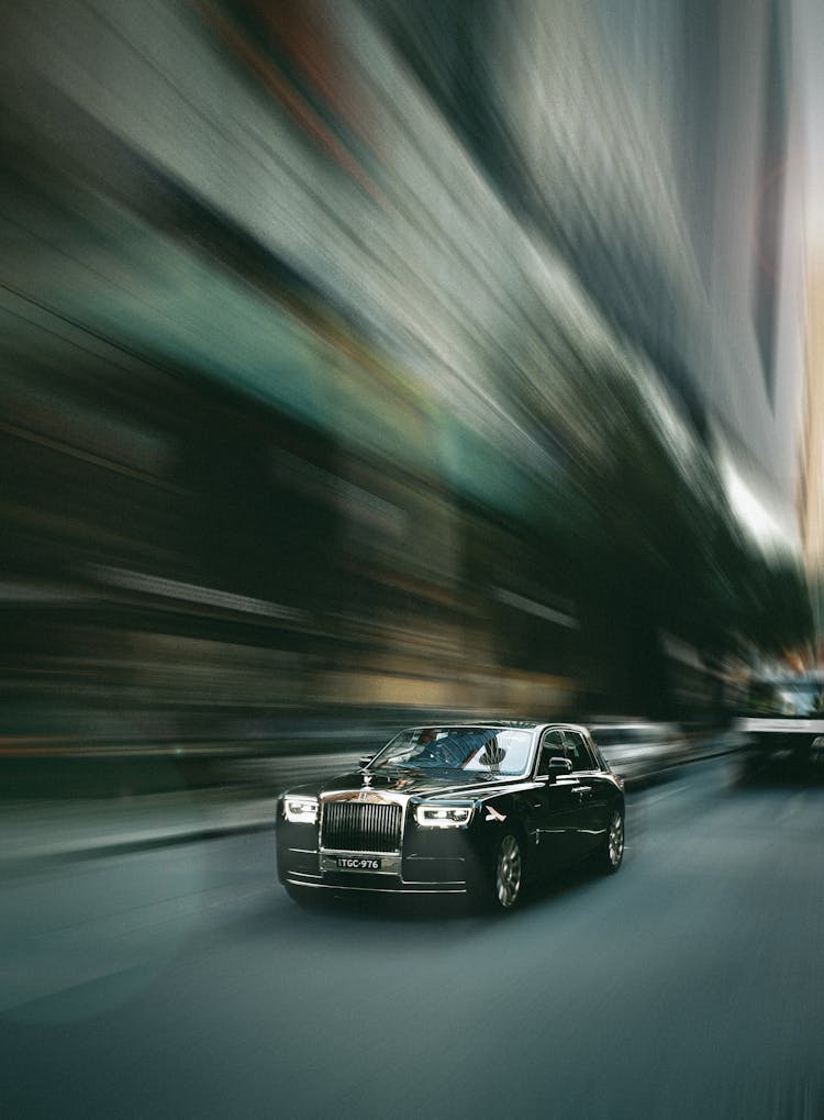 Black Rolls-Royce Racing Fast Down Street Of City