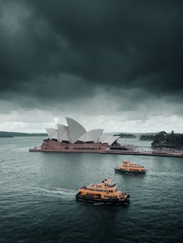 Moody view of Sydney Opera House with ferries under ominous clouds.