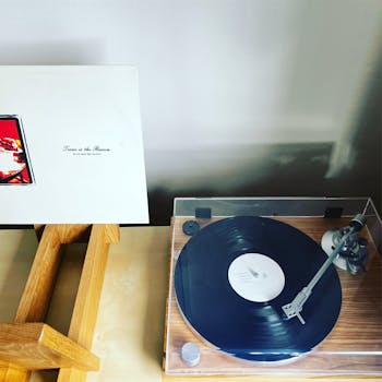 Vinyl record on a turntable next to an album cover on display.