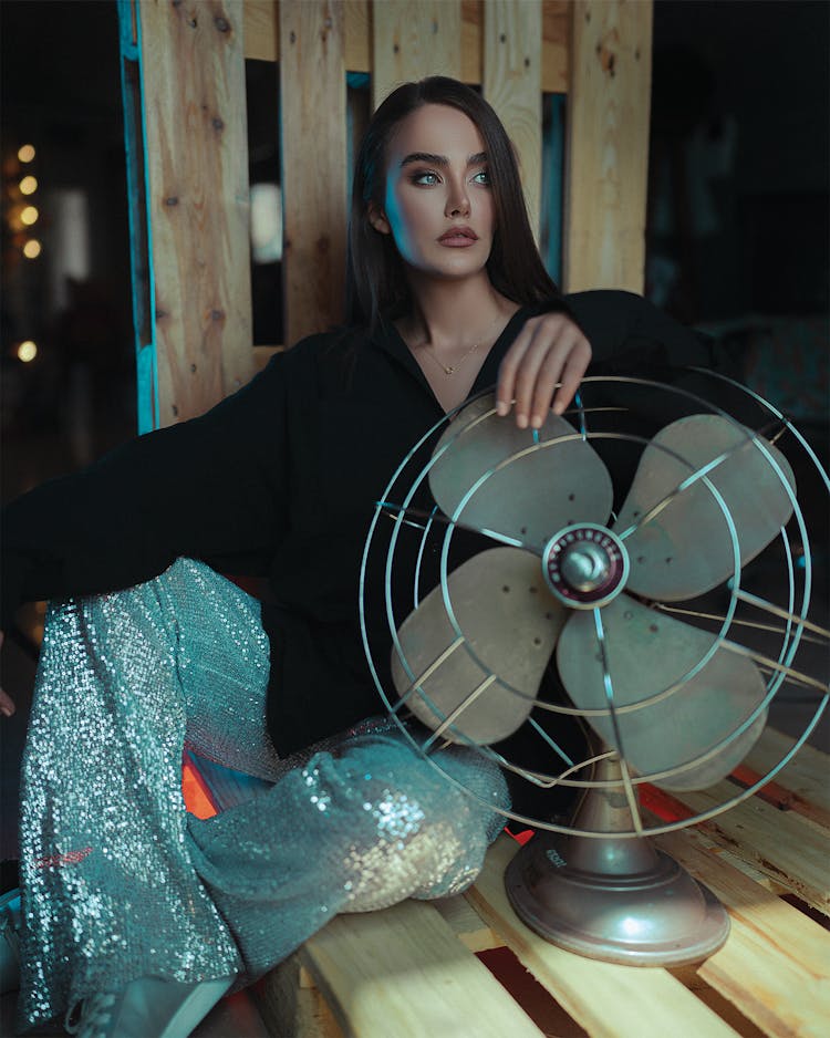 Woman Sitting On Pallet And Holding Fan