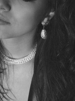 Close-up grayscale portrait featuring a woman with pearl necklace and earrings, capturing elegance and style.