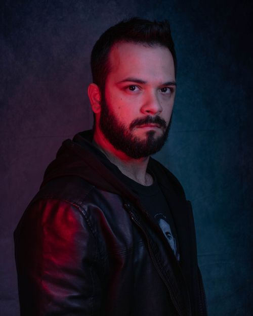Free A striking portrait of a bearded man in a leather jacket with dramatic lighting, taken in a studio. Stock Photo