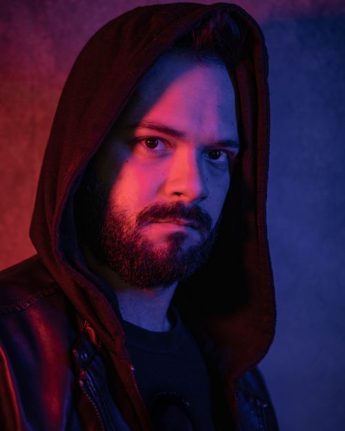 Free Intense portrait of a man wearing a hoodie, highlighted by dramatic lighting. Stock Photo