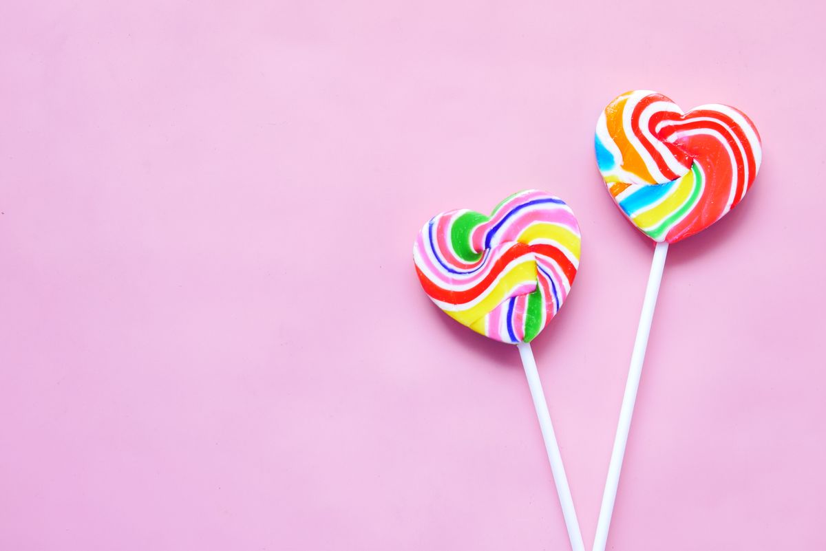 Vibrant heart-shaped lollipops against a light pink background, perfect for sweet-themed designs.