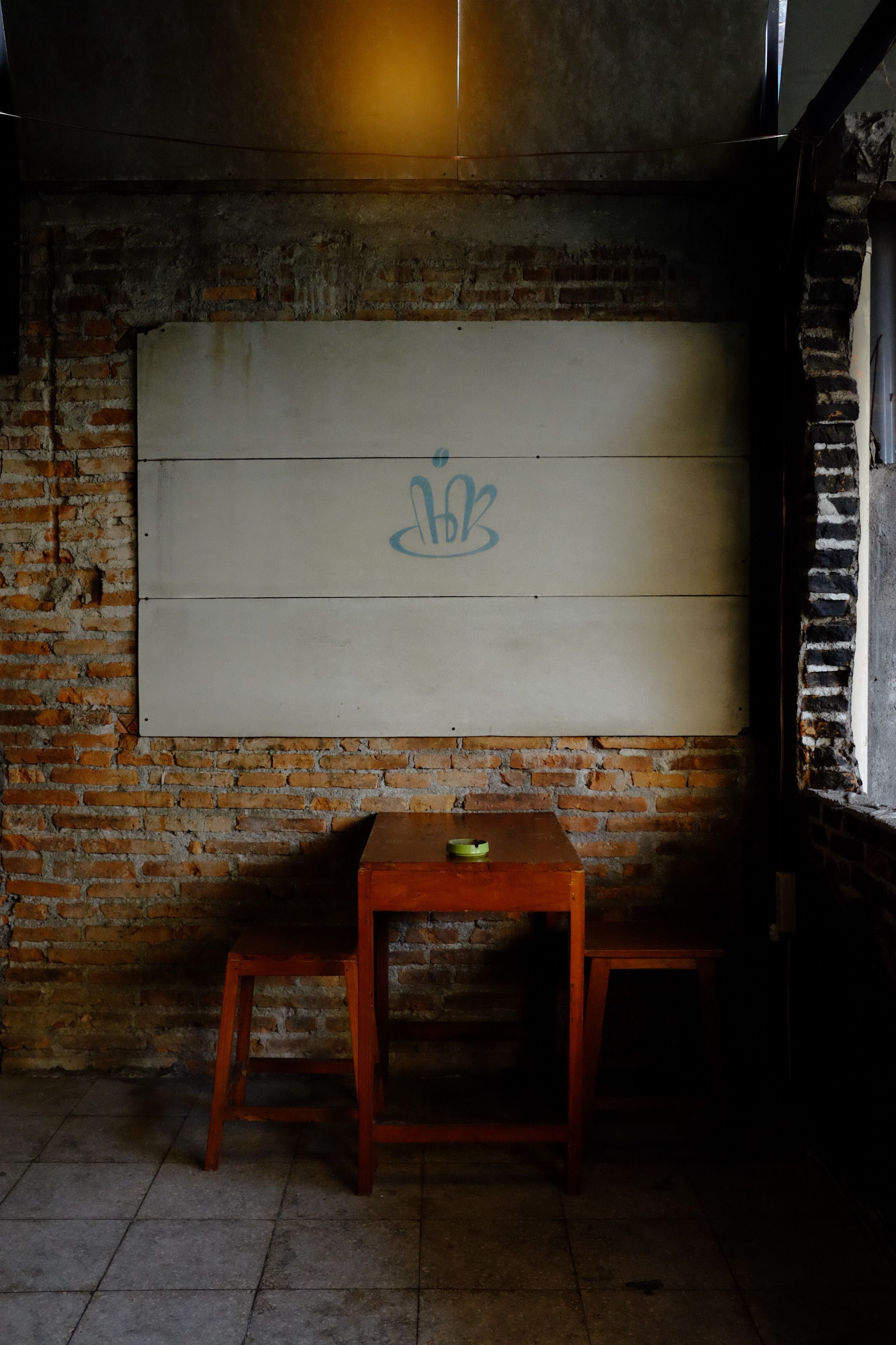 Dimly lit abandoned room with brick wall and wooden furniture.