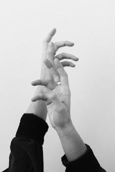 Studio shot of hands making gestures with rings in a minimalist black and white style.
