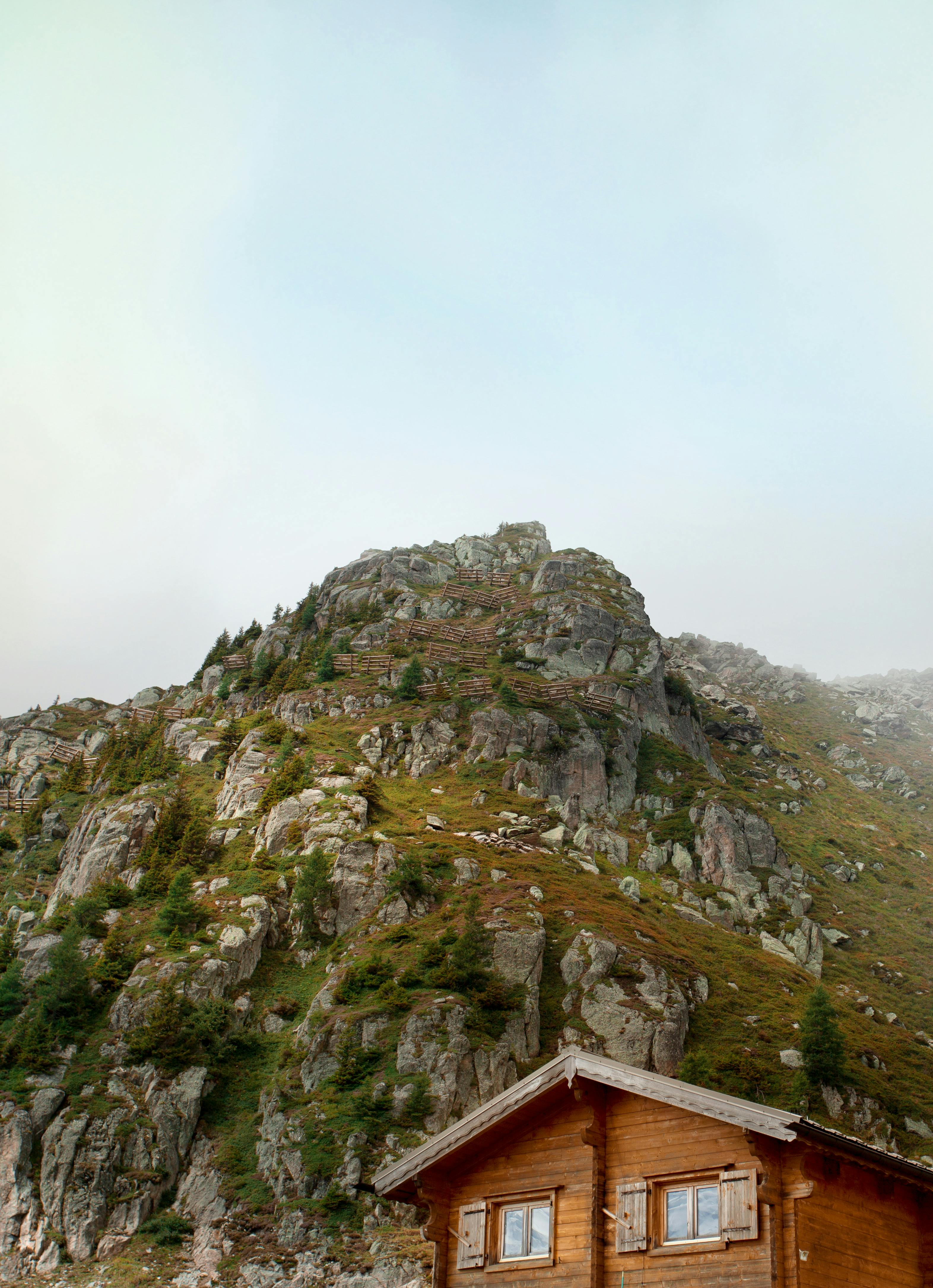 A scenic view of a wooden chalet nestled below a rocky mountain in Chamonix, France.