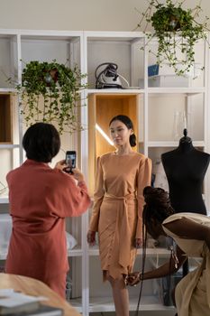 Three women in a modern fashion studio working on a stylish dress design, perfect for showcasing creative collaboration.