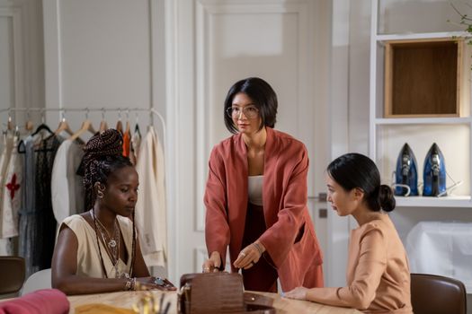 Three diverse women designers working together in a fashion studio, planning and discussing ideas.