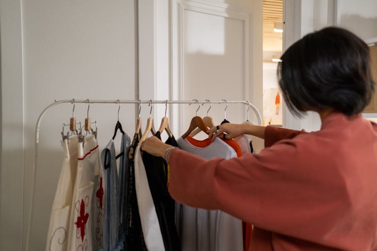 Rear View On Woman Checking Clothes On Rack