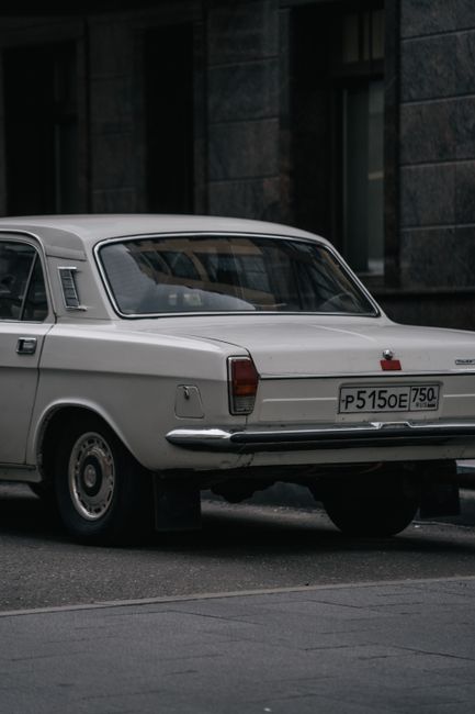 A close-up of a classic white vintage car parked on an urban street with a moody atmosphere.