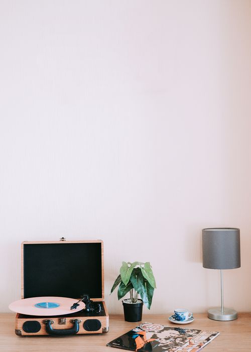 Free A retro-themed desk with a turntable, vinyl records, a potted plant, and a lamp. Stock Photo