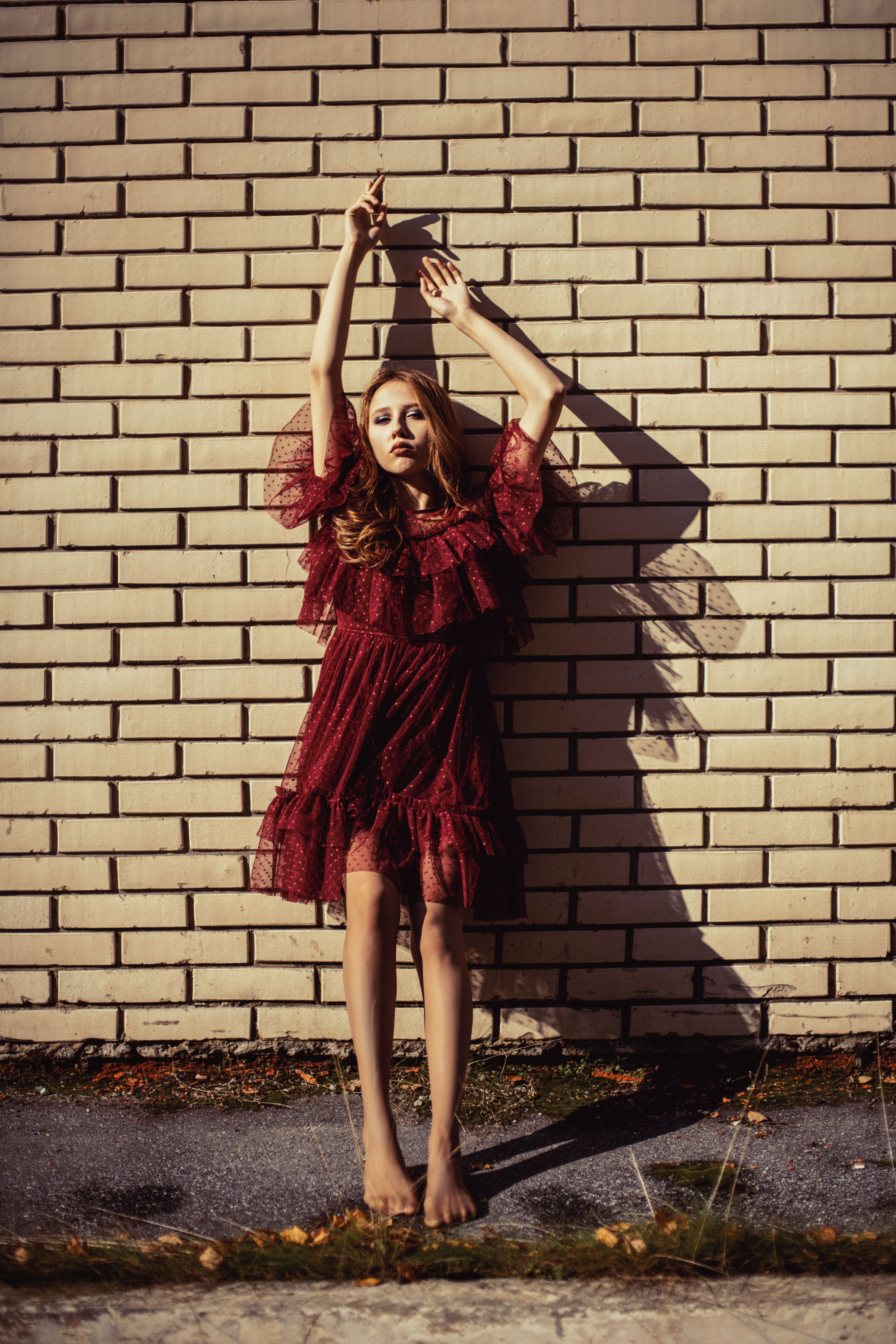 Woman Leaning on Wall while Raising Her Hands