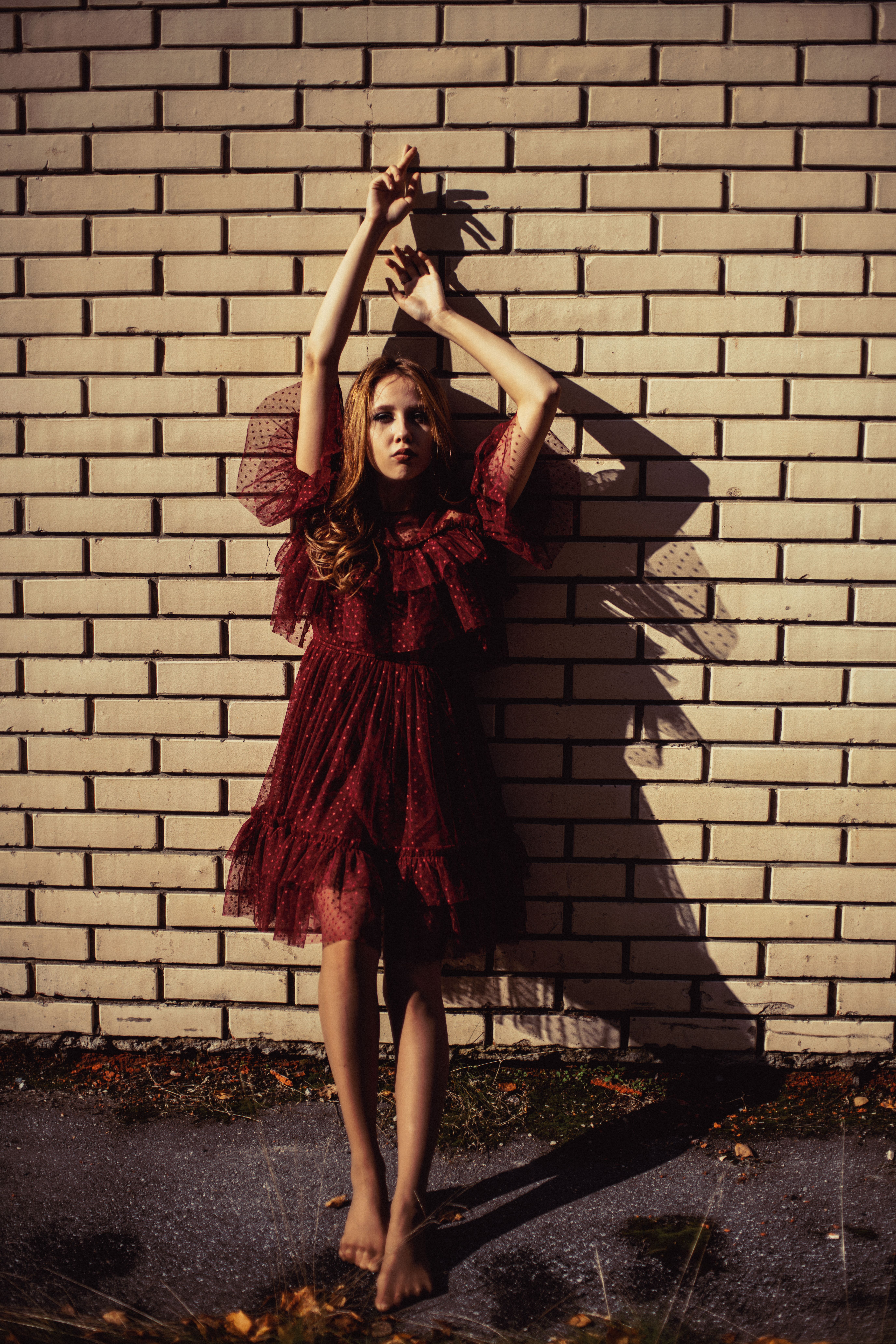 Woman in Red Dress Standing Beside the Brick Wall
