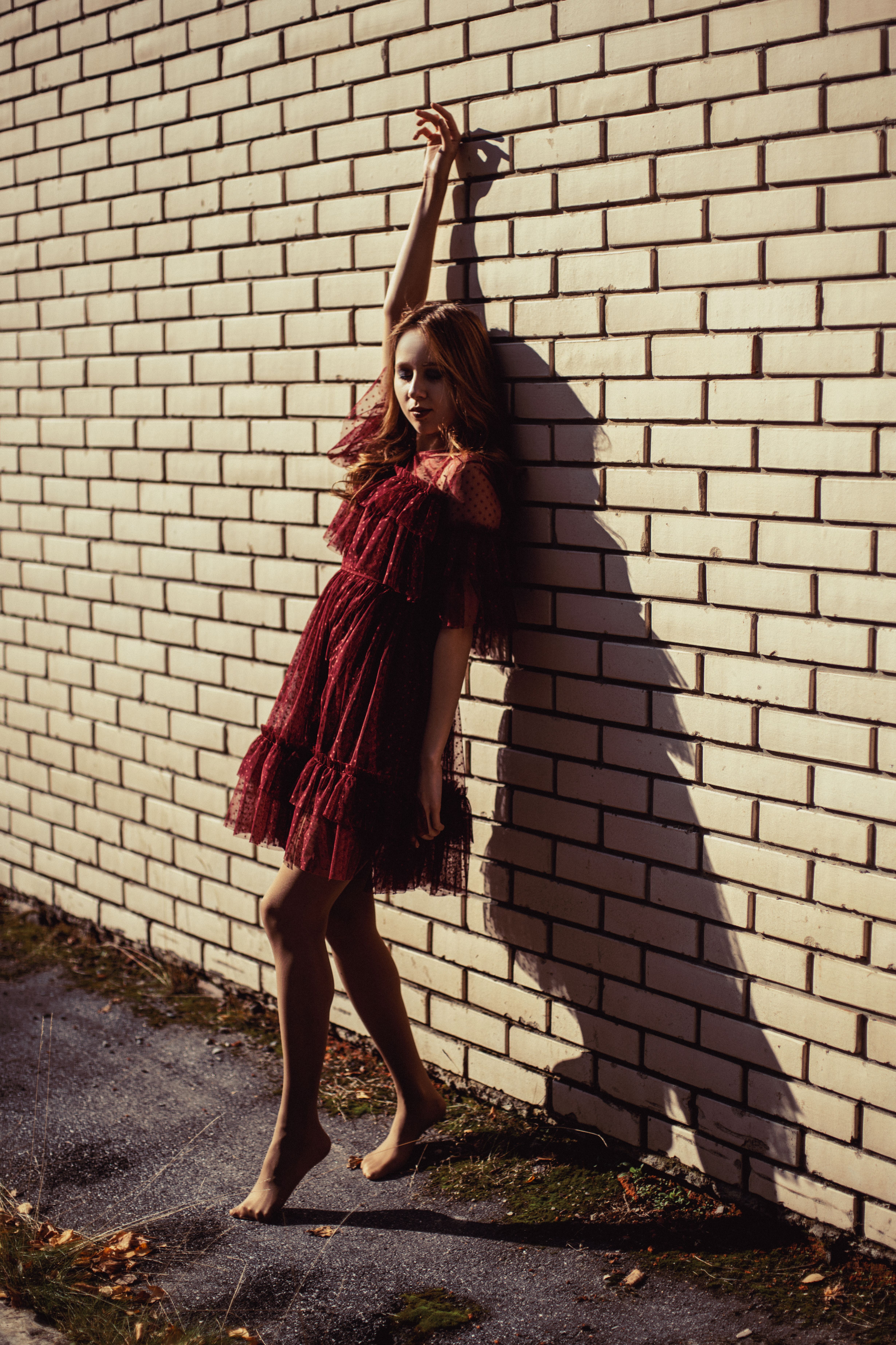 Woman Leaning on Brick Wall with Her Hand Raised