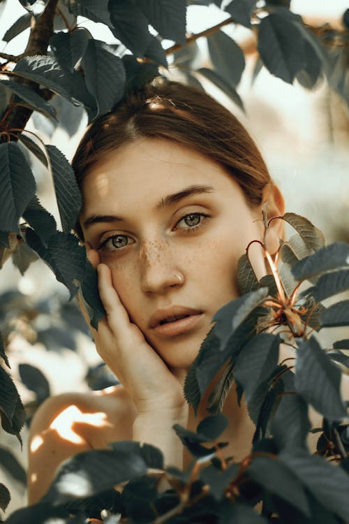 Girl with Ginger Hair Hidden behind Branches with Leaves