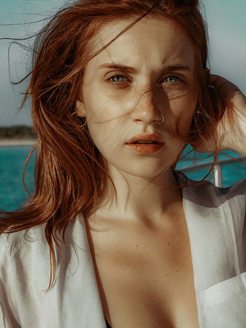 Free Close-up portrait of a woman with red hair and nose piercing at the beach. Stock Photo