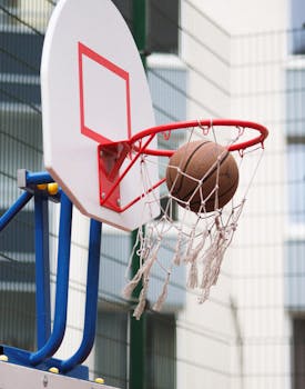 Close-up of a basketball scoring in an outdoor hoop against a city backdrop.