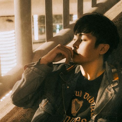 Free Thoughtful young man in a denim jacket, basking in warm indoor lighting. Stock Photo