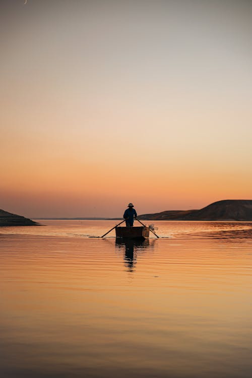 Silhouette of Person Paddling on a Boat During Sunset