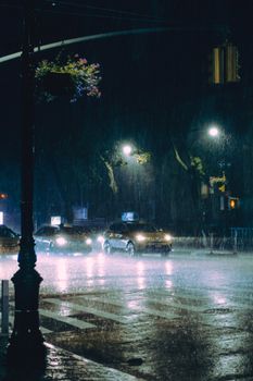 A city street at night with cars and streetlights in a rainstorm, showing urban nightlife.