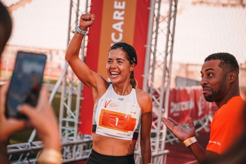 Free Female athlete celebrates marathon victory with a fist pump and winning smile. Stock Photo