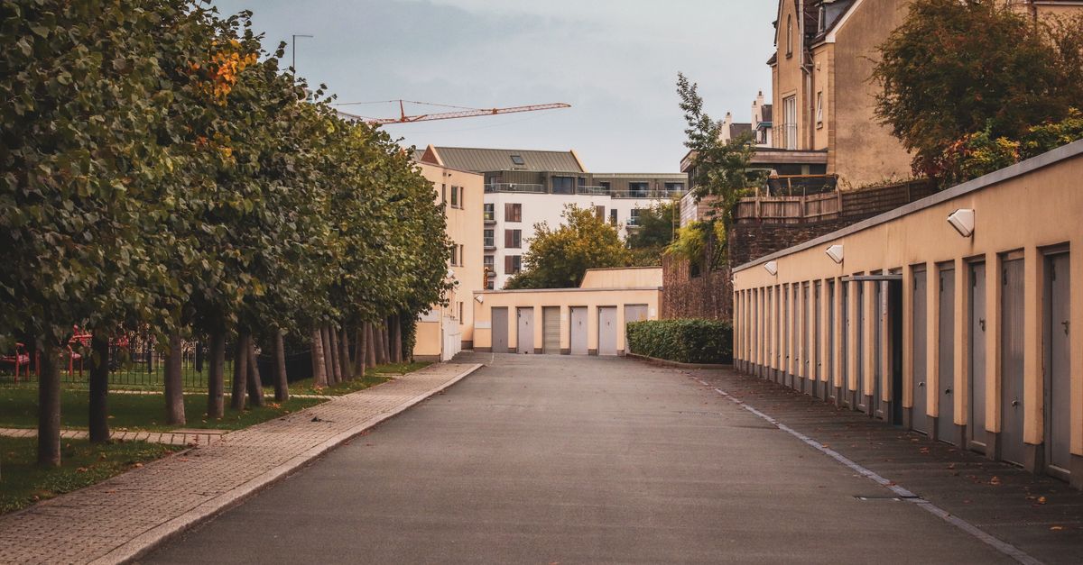 Quiet urban alleyway flanked by residential buildings and trees, offering a serene cityscape vibe.
