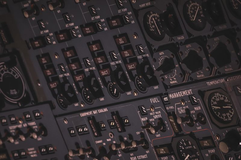 Close-up of an aircraft cockpit's black and gray instrument panel with dials and switches