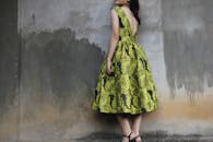 以时尚照片为模型的花卉连衣裙，背景是质朴的混凝土墙