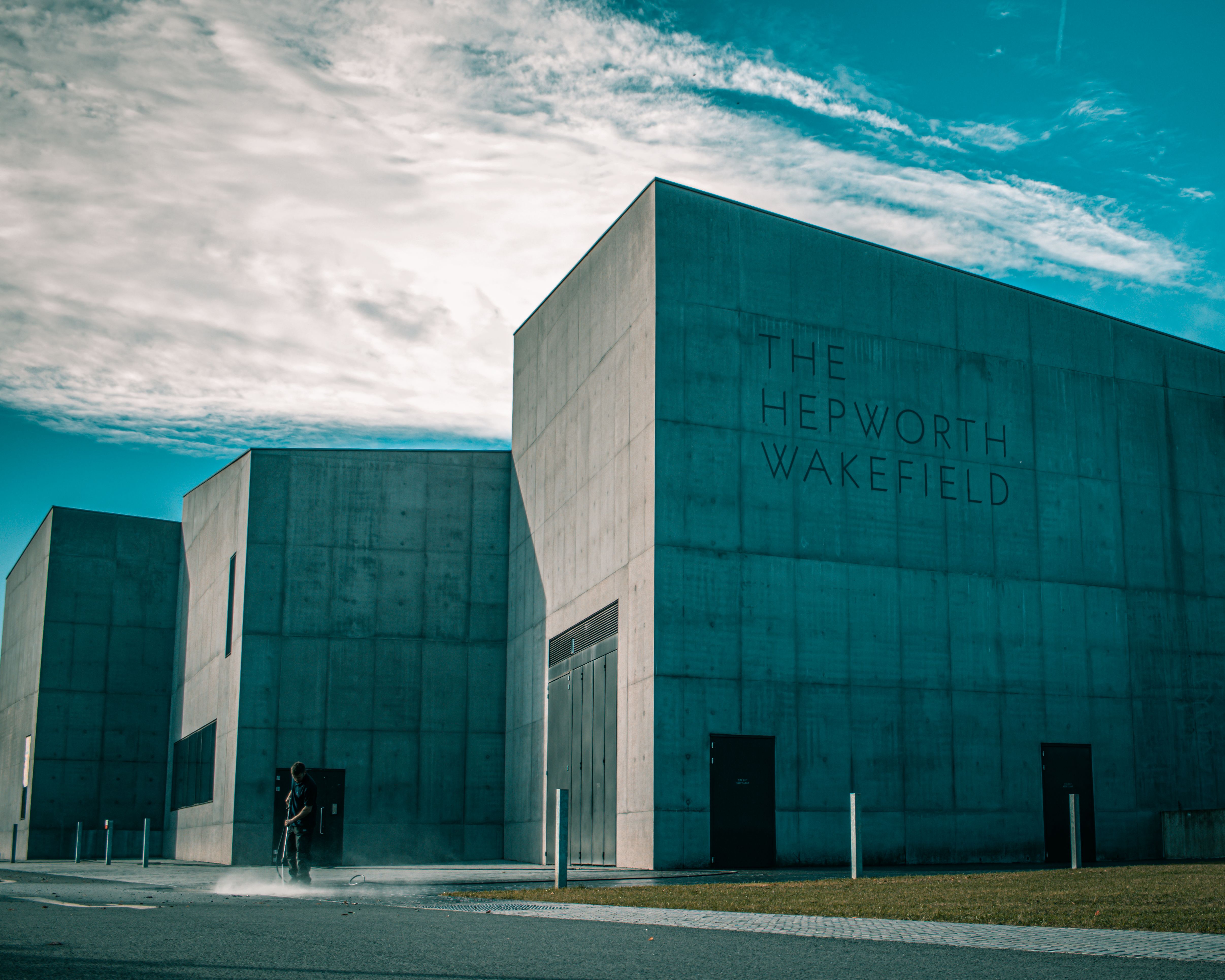 Low-angle view of The Hepworth Wakefield under a cloudy blue sky, displaying modern architecture.
