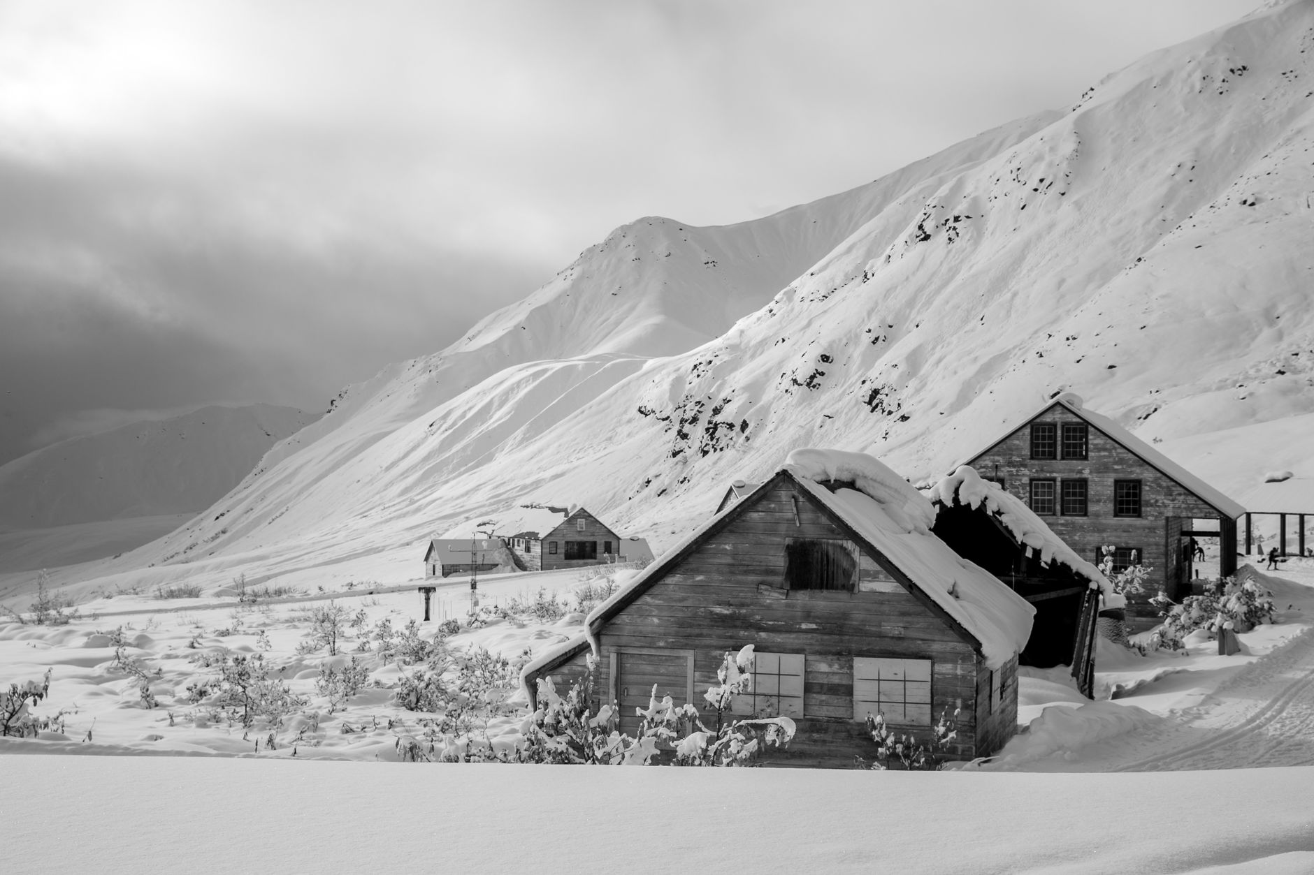 Snow-covered cabins surrounded by Alaska mountains in winter.