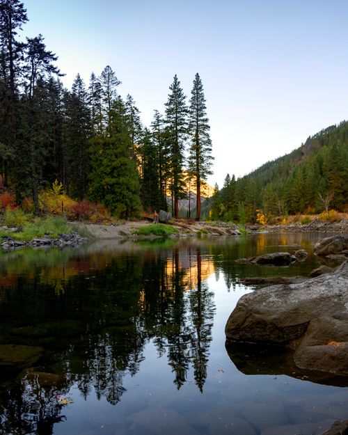 Free Calm river reflecting a lush forest and sky, creating a serene nature scene in Washington. Stock Photo