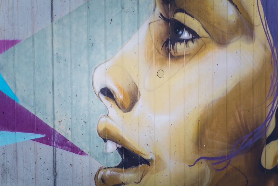 Close-up of colorful street art depicting a woman's face on a concrete wall.