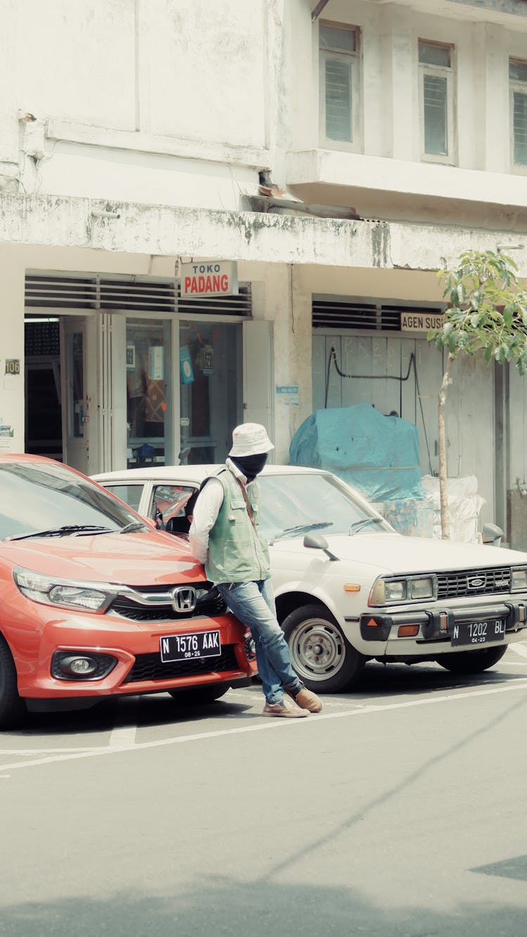 Person Wearing Black Face Mask Leaning On The Orange Car 