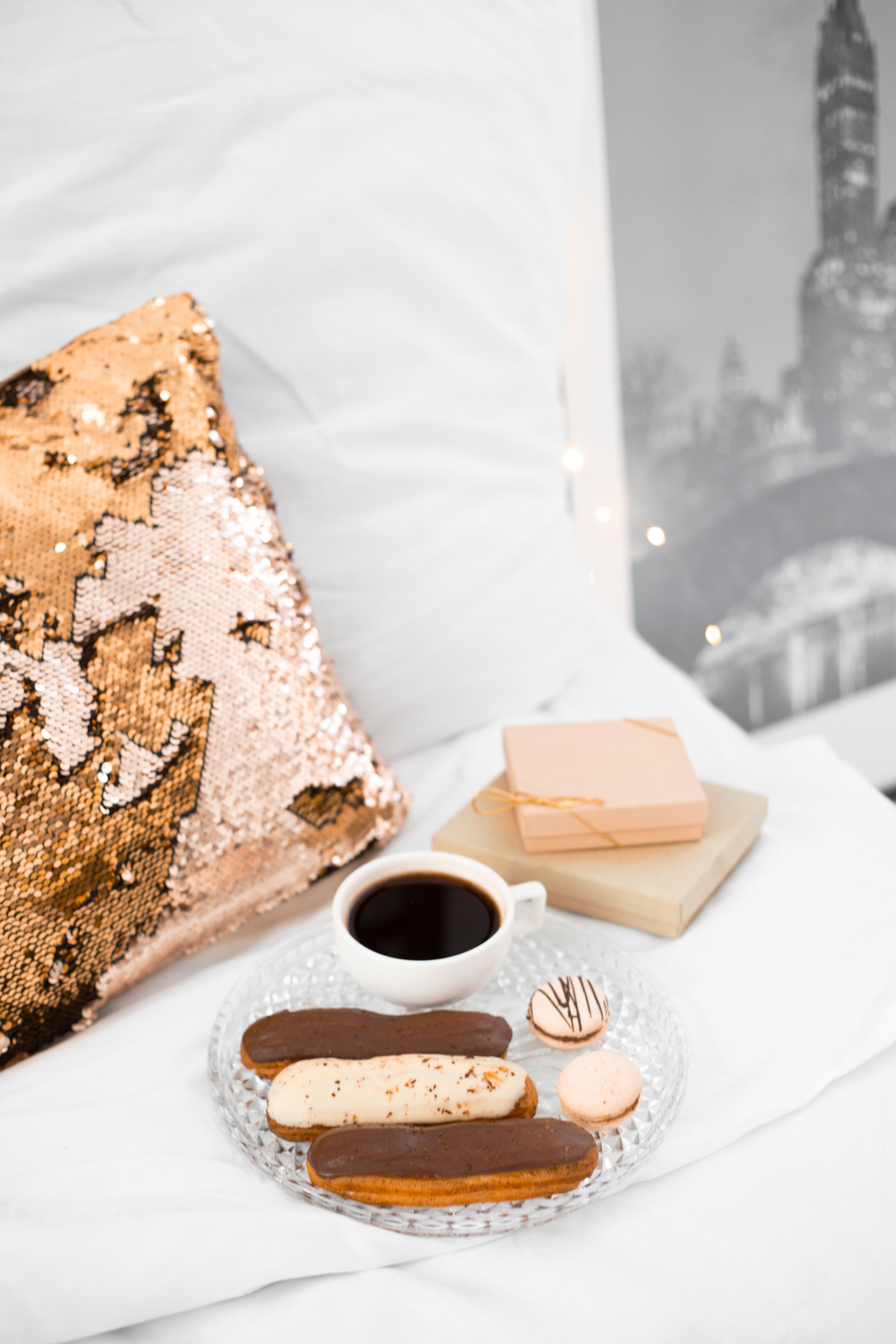 Cup of coffee with pastries on a bed, featuring elegant decor for a cozy, relaxing morning.