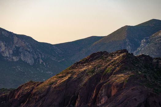 Scenic view of rugged mountains under warm sunset light, showcasing natural beauty and tranquility.