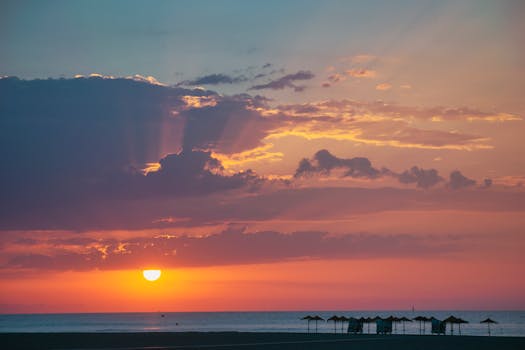 Breathtaking sunset over a tranquil beach with dramatic clouds and vibrant colors.