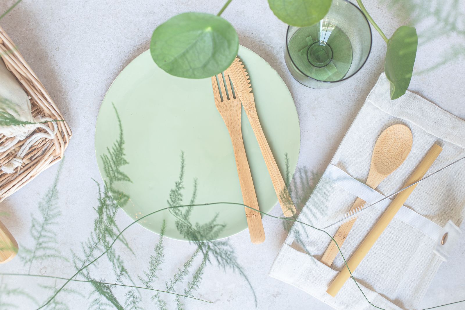 Flat lay of bamboo utensils on a green plate with eco-friendly theme.