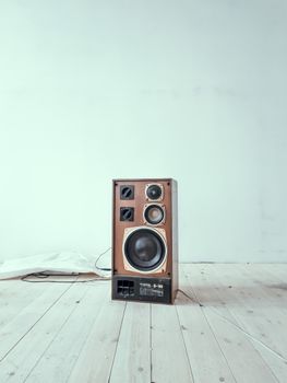 Vintage wooden speaker placed centrally on a light wooden floor with copy space.