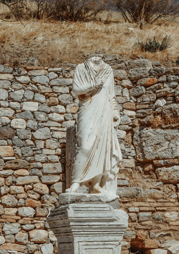 Ancient Statue Near Brick Wall In Nature