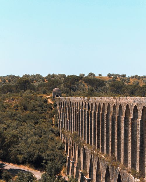 Free Explore the historic aqueduct in Portugal, set in a lush landscape under a bright sky. Perfect for travel enthusiasts. Stock Photo