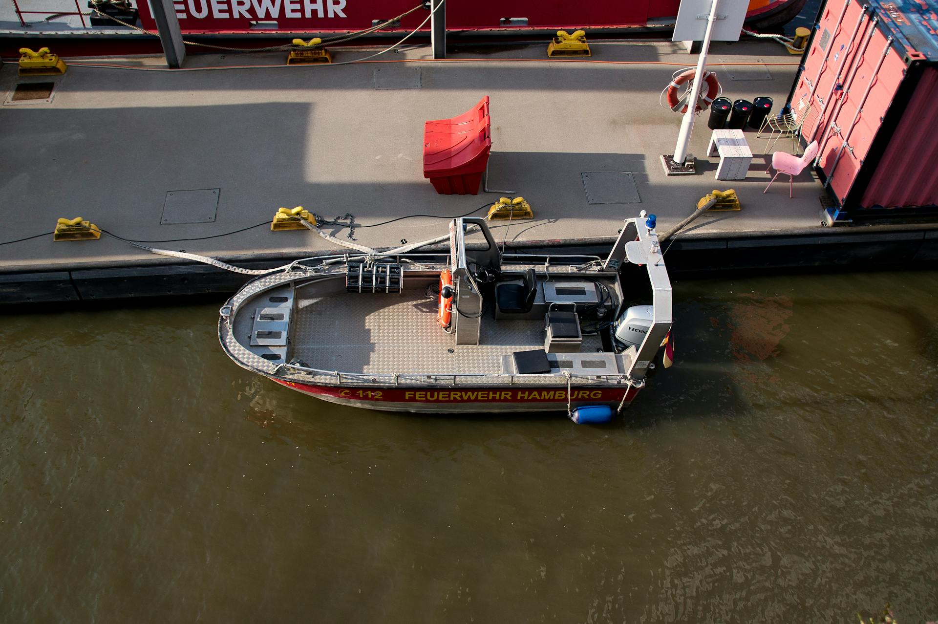 A firefighting boat docked at Hamburg harbor under sunlight, ready for emergencies.