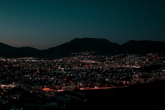 A breathtaking aerial view of a cityscape with glowing city lights under a dark sky, highlighting the urban landscape at night.
