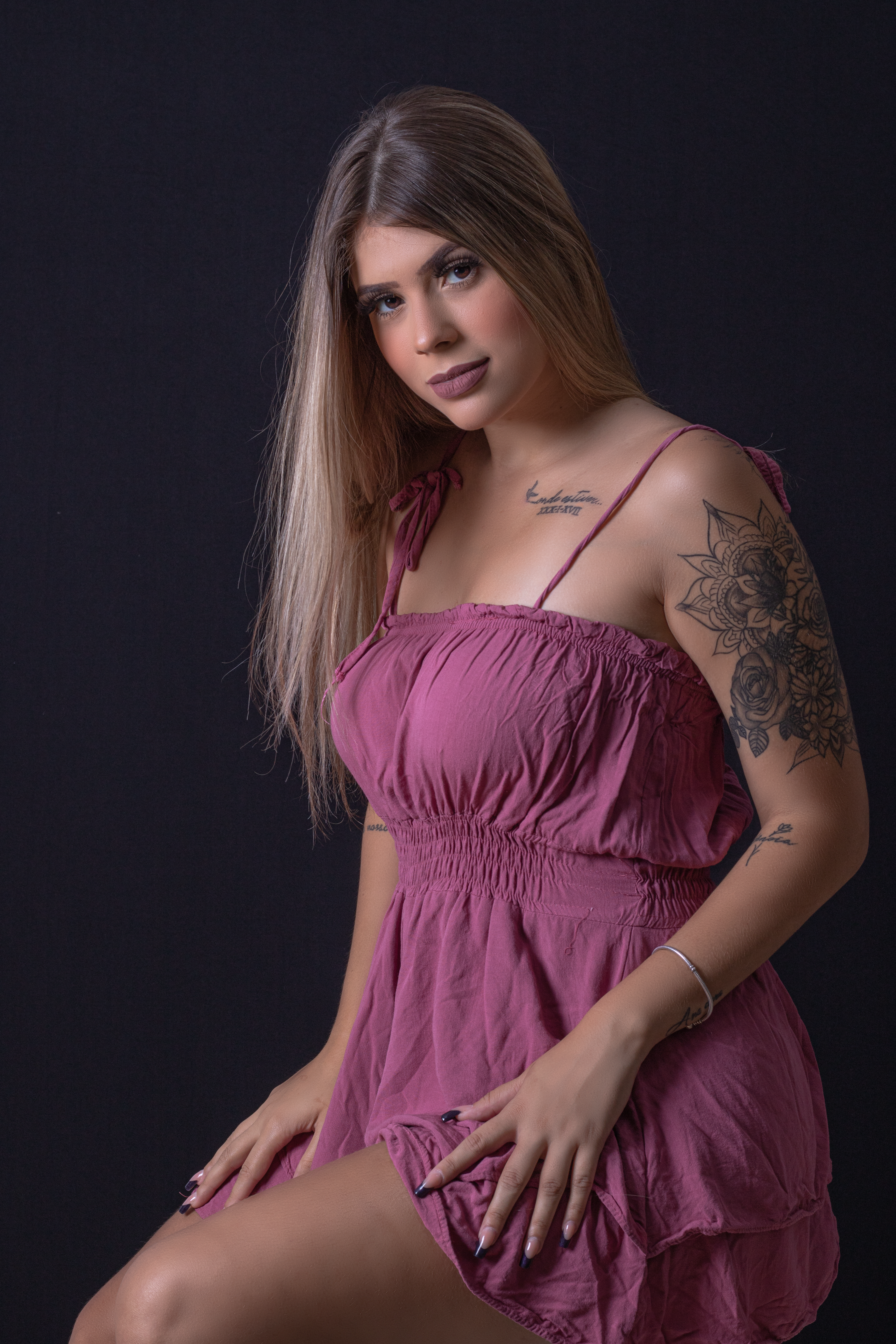 Studio portrait of an elegant woman in a pink dress with floral tattoos.