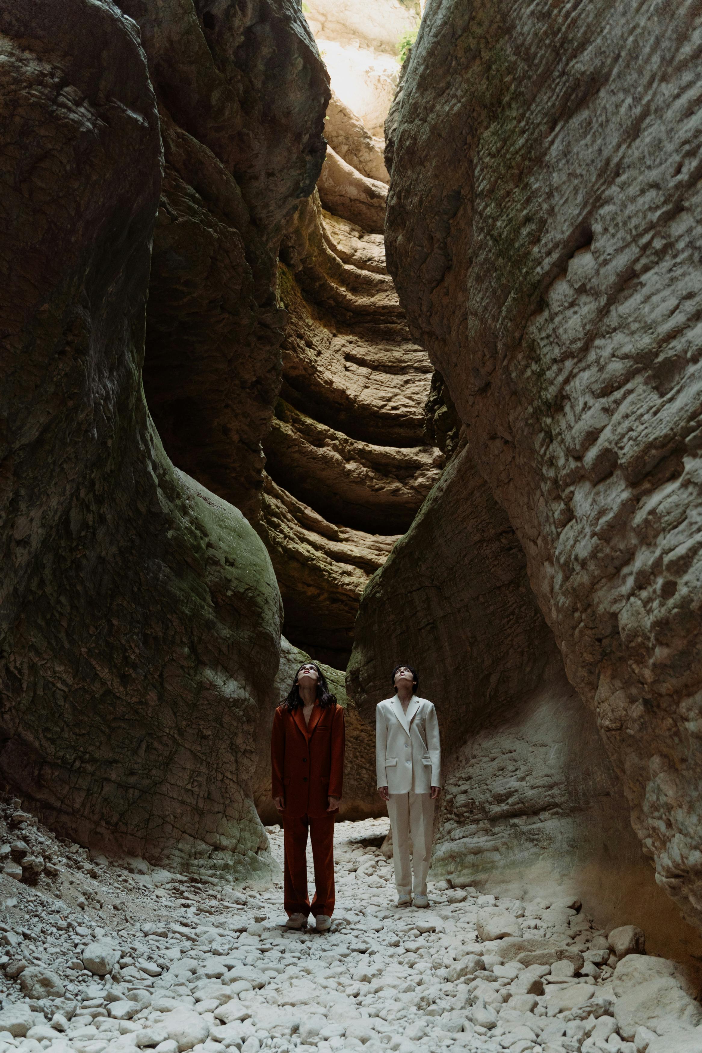 models wearing stylish suits standing between gigantic rocks