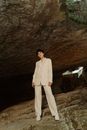 Man in White Suit Standing on Brown Rock