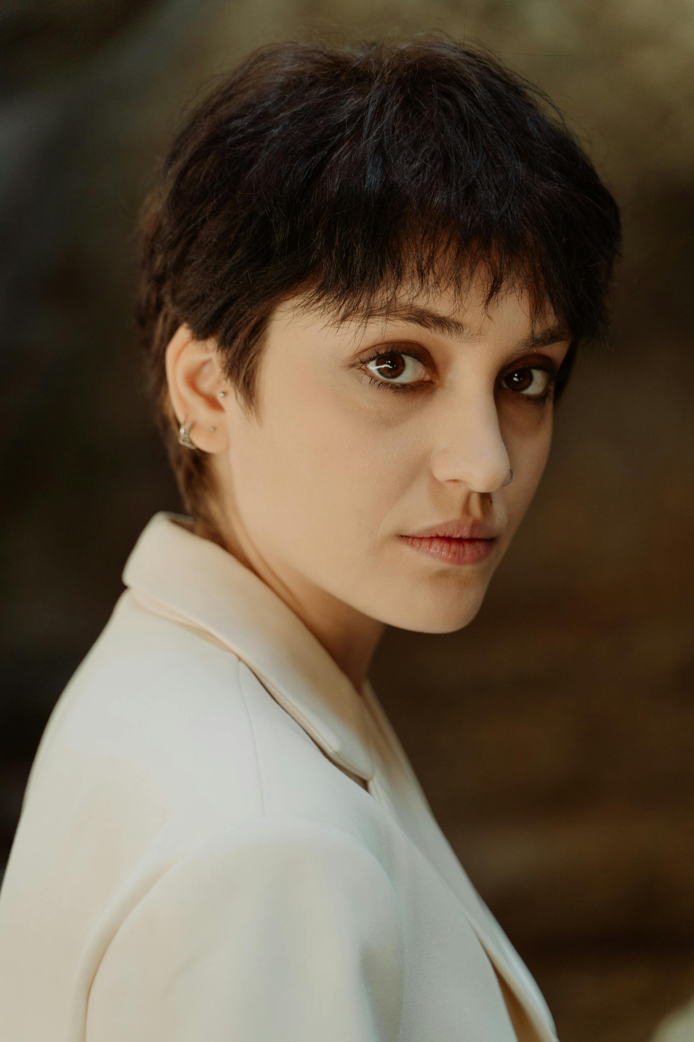 Professional portrait of a woman in a cream suit, exuding elegance and confidence in an outdoor setting.