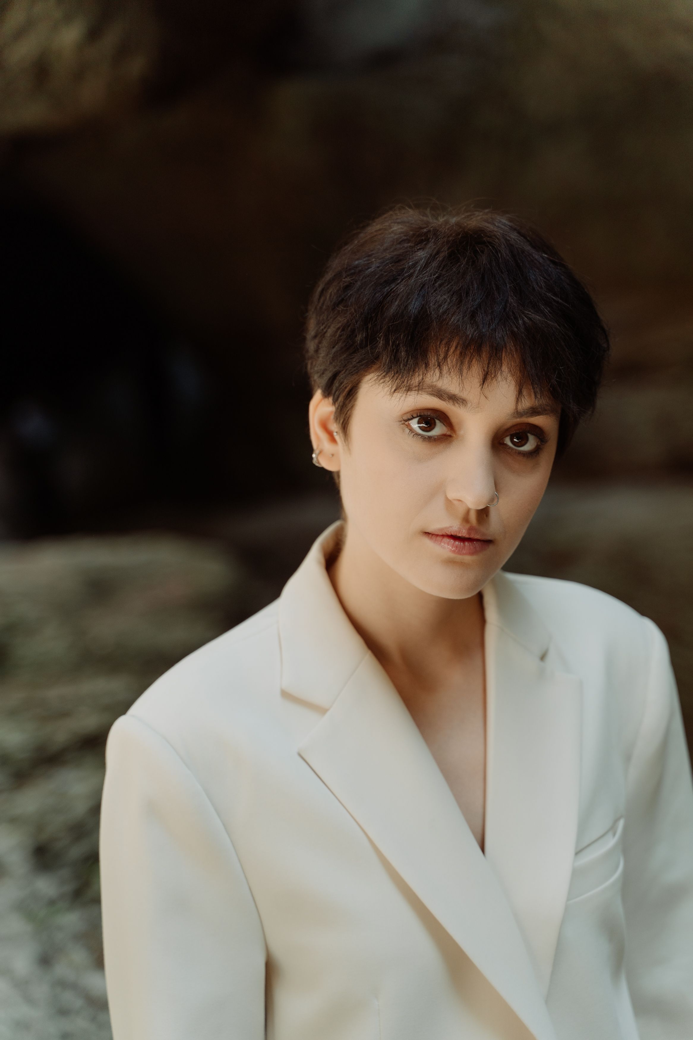 Captivating portrait of a woman in a white blazer with a natural background.