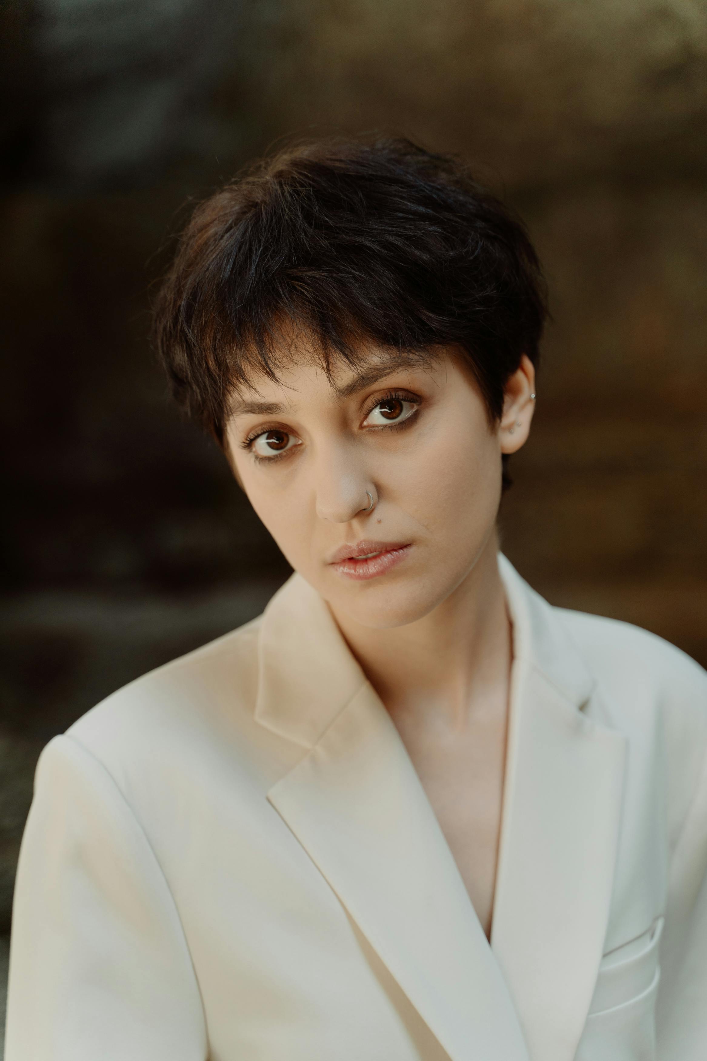 Portrait of a young woman with short hair in a white blazer, exuding elegance.